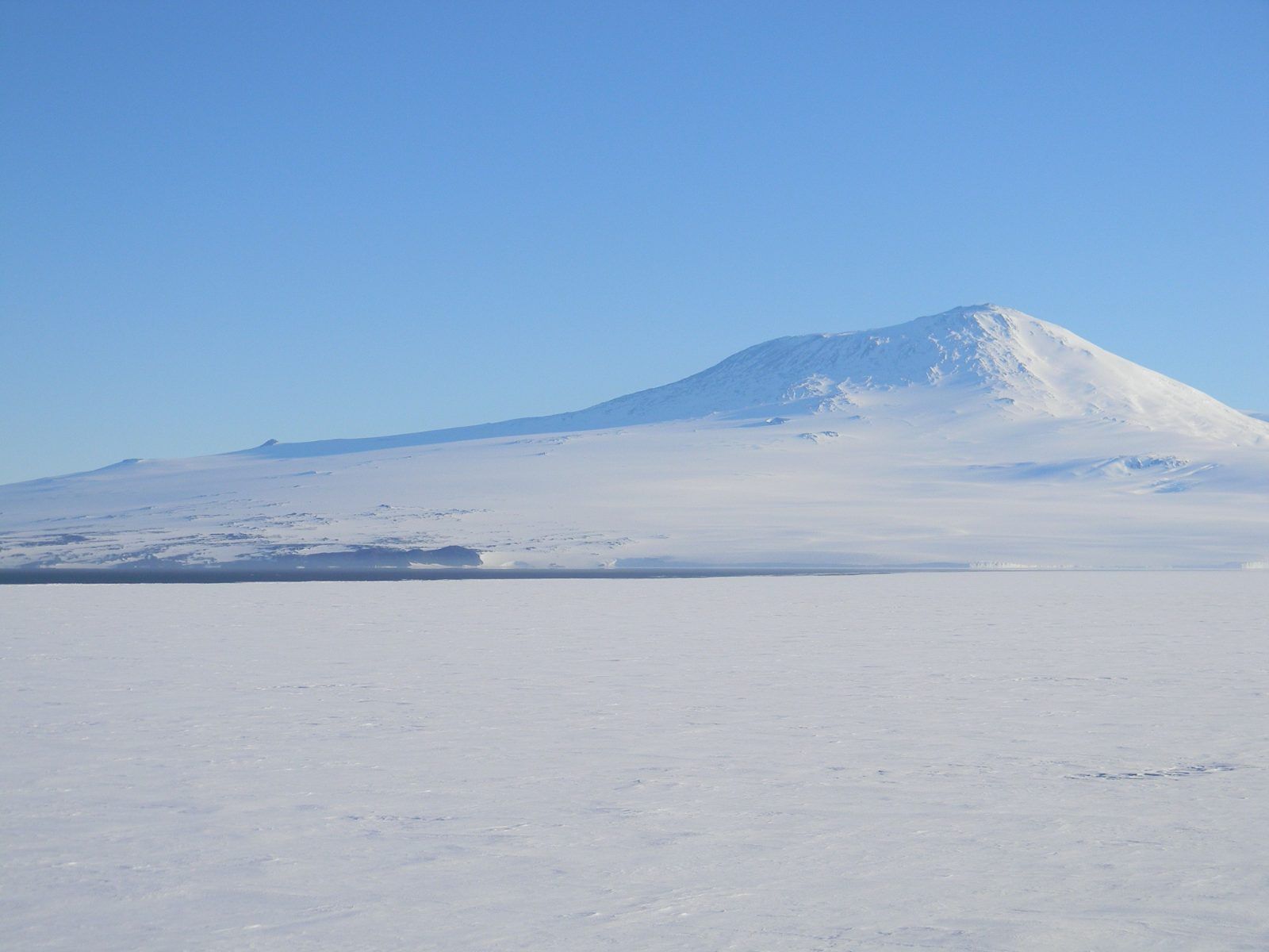 Snow plain below a broad volcano