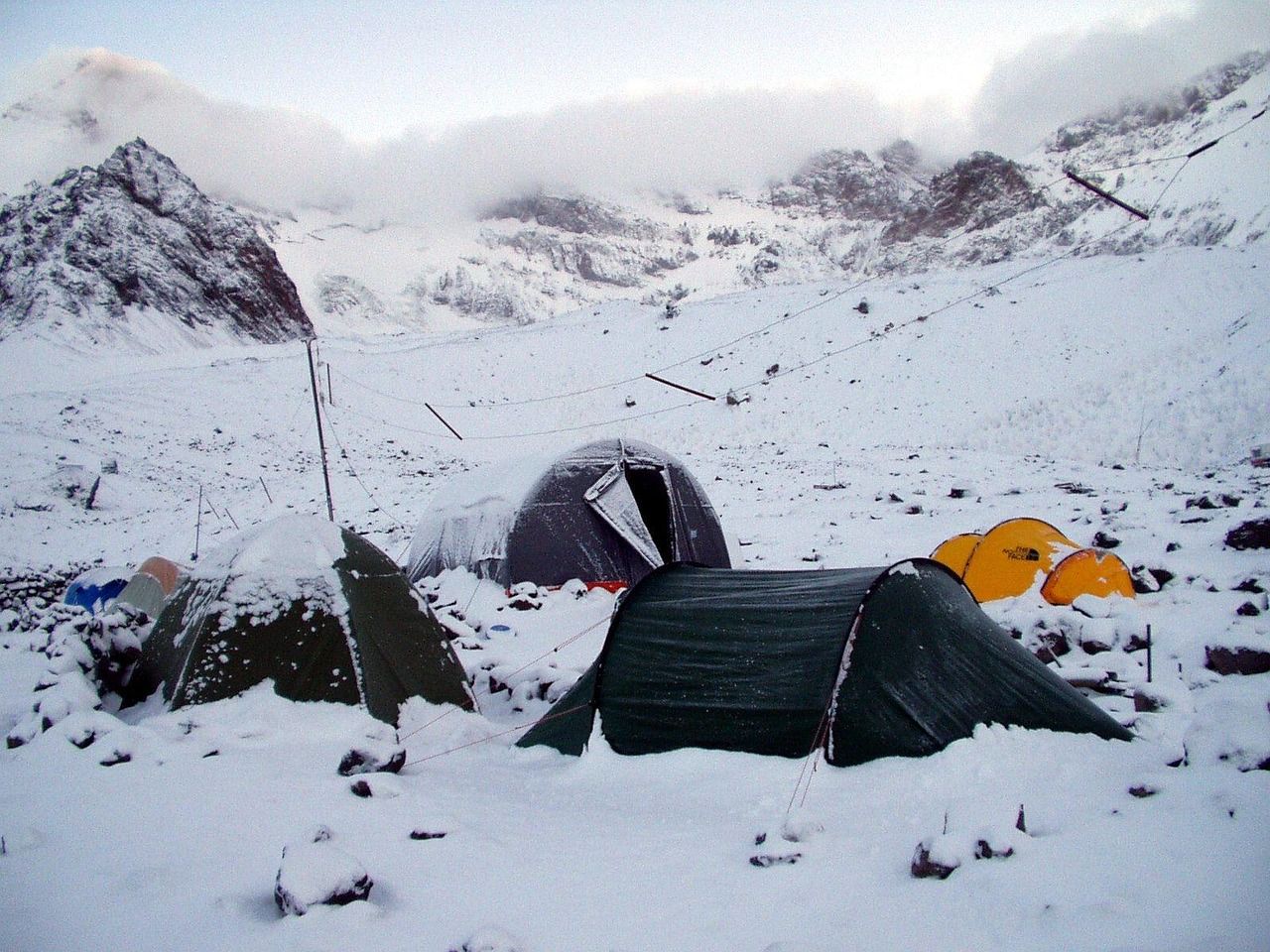 Tents pitched among rock and snow in a valley