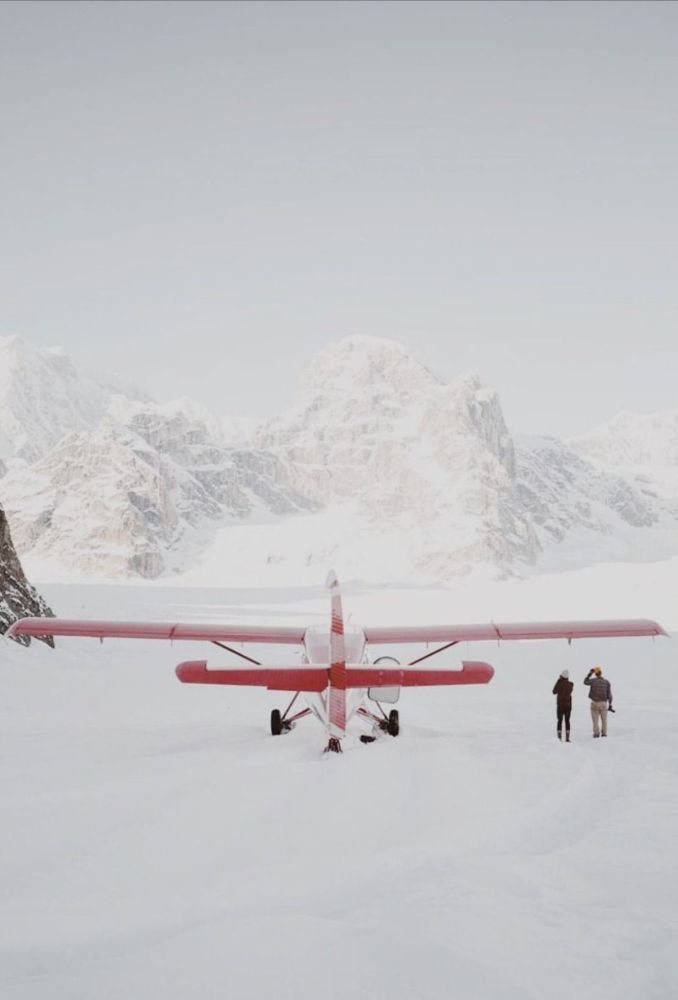 Red ski plane with two people on a snowfield