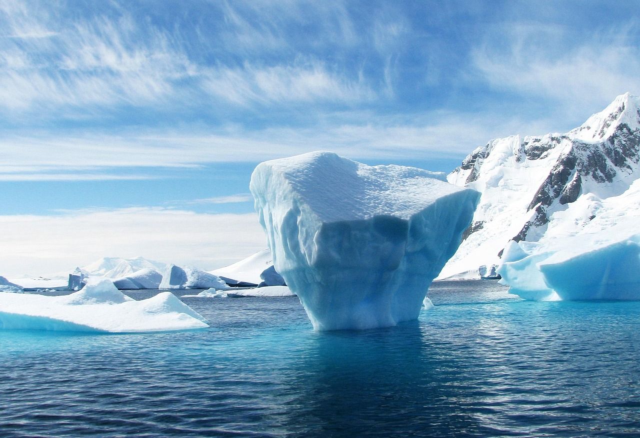 Blue iceberg in a bay below snow peaks