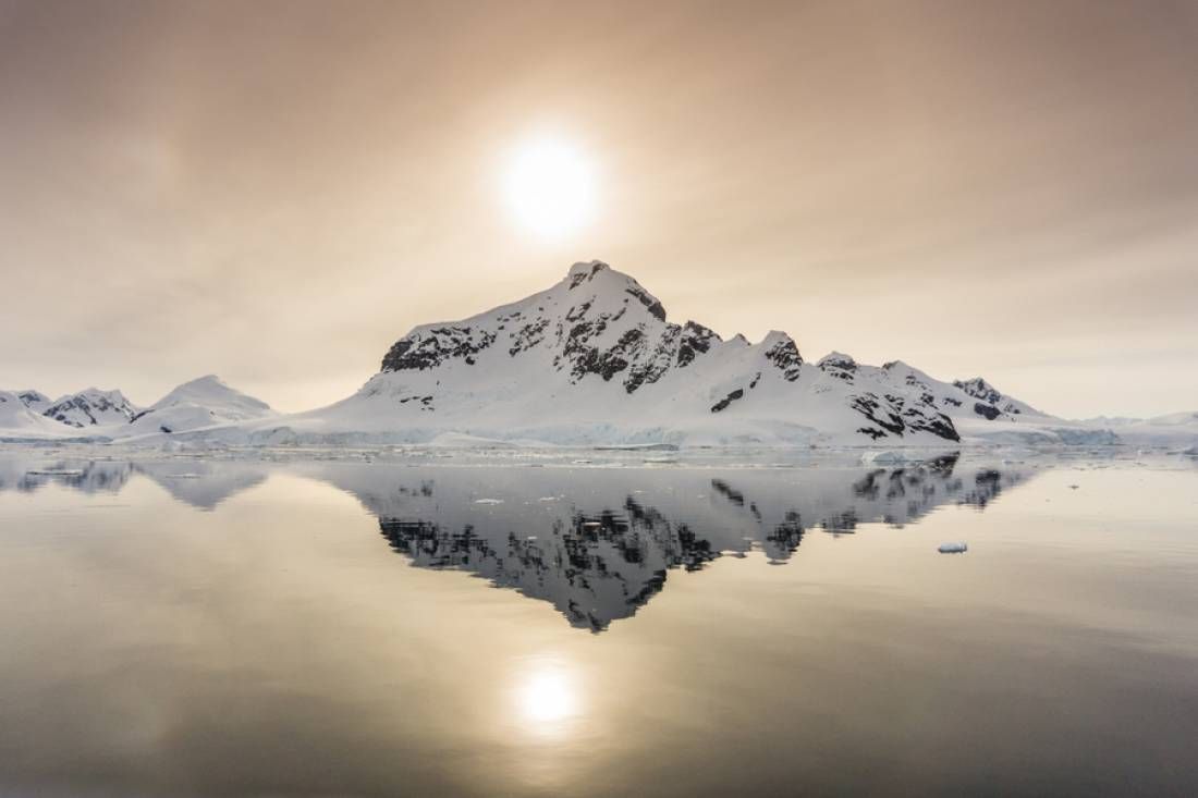 Low sun reflected under a snow peak