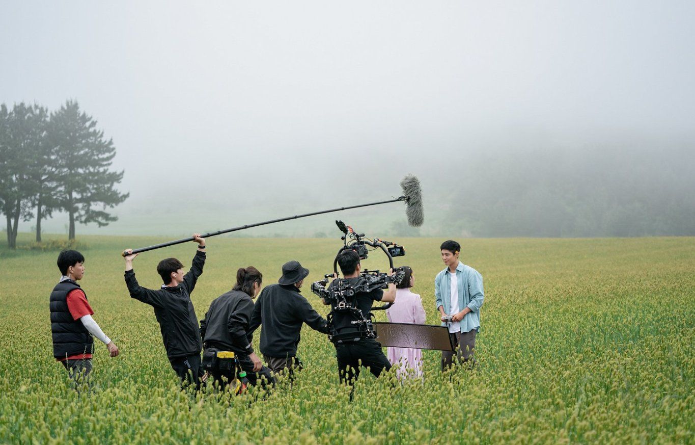 Crew with a boom mic in a misty field
