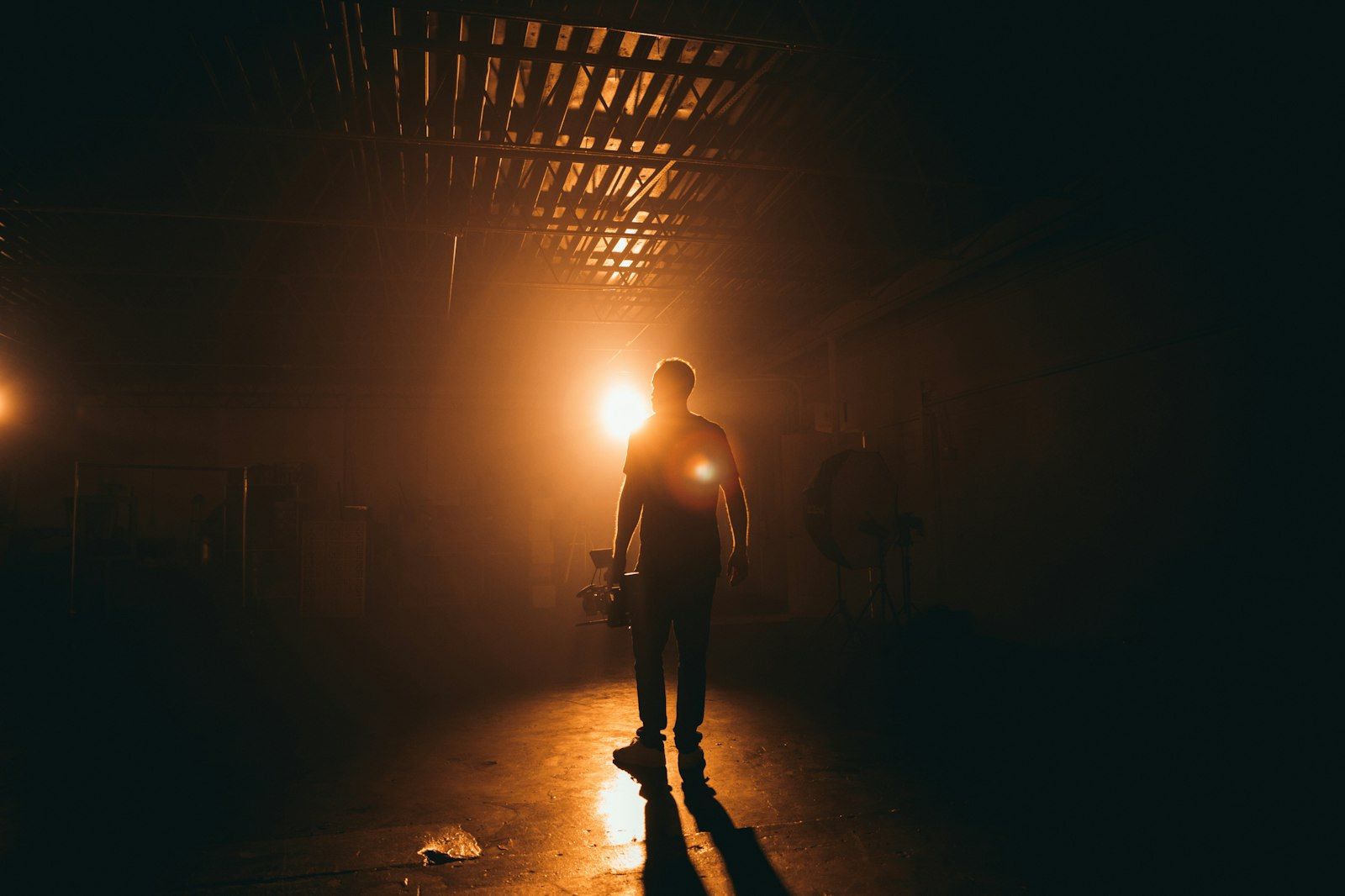 Figure backlit in a dark warehouse