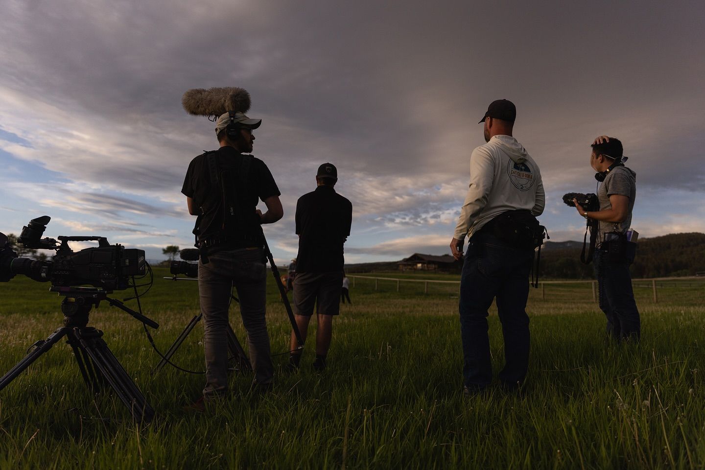 Crew silhouettes with a camera rig in a field at dusk