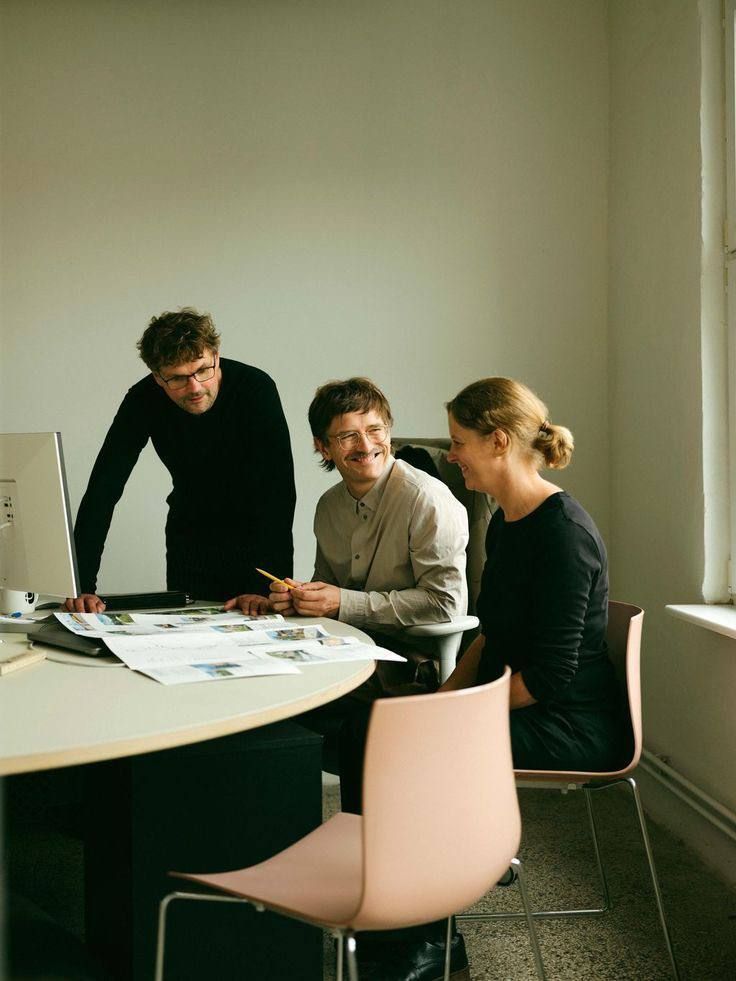 Three colleagues laughing around a table of printouts
