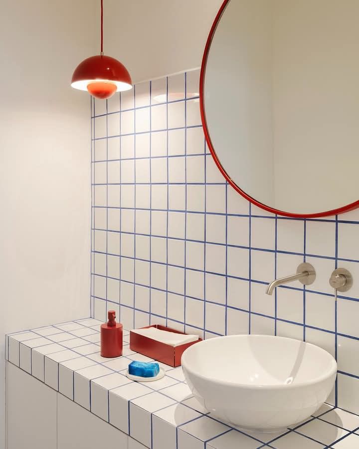 White tiled bath with a red round mirror