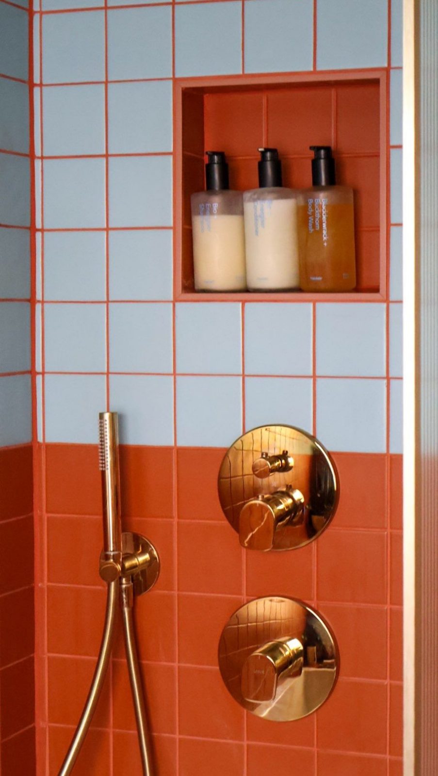 Orange and pale blue tiles with brass shower fittings