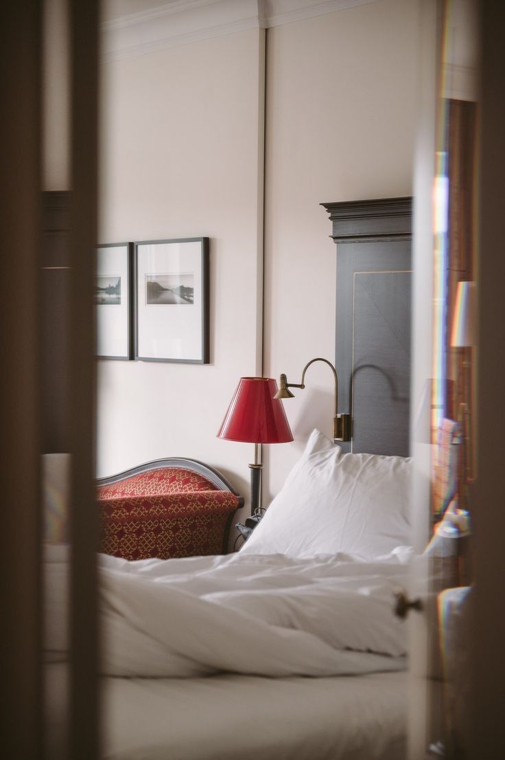 White bed beside a red wall lamp