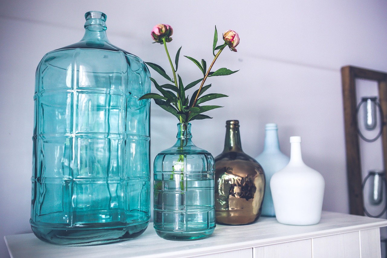 Glass bottles and a stem of peonies on a shelf