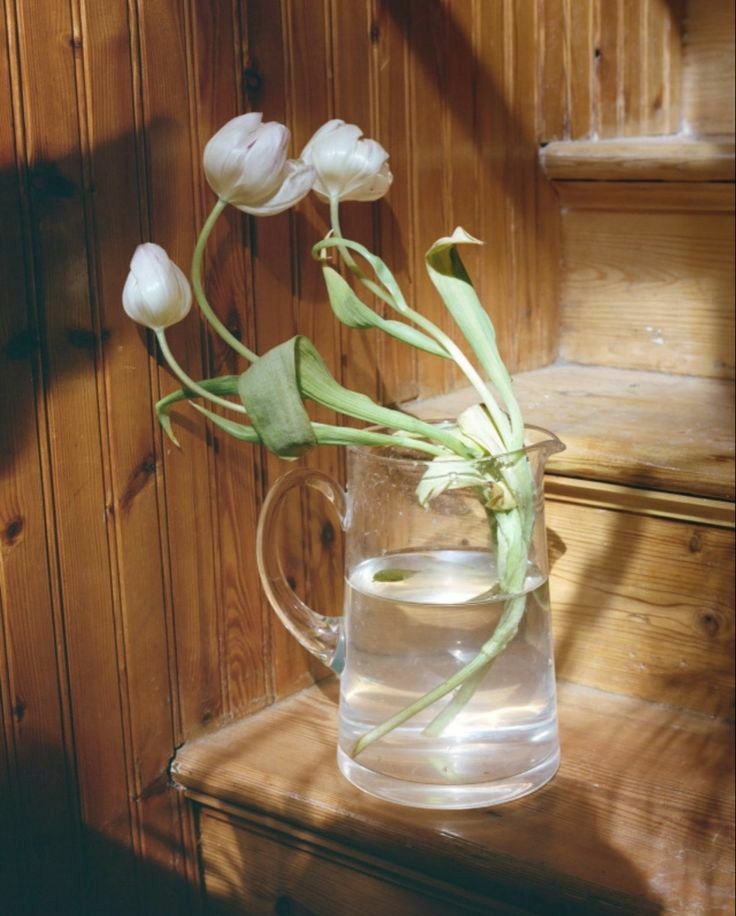 Tulips in a glass jug on a wooden step