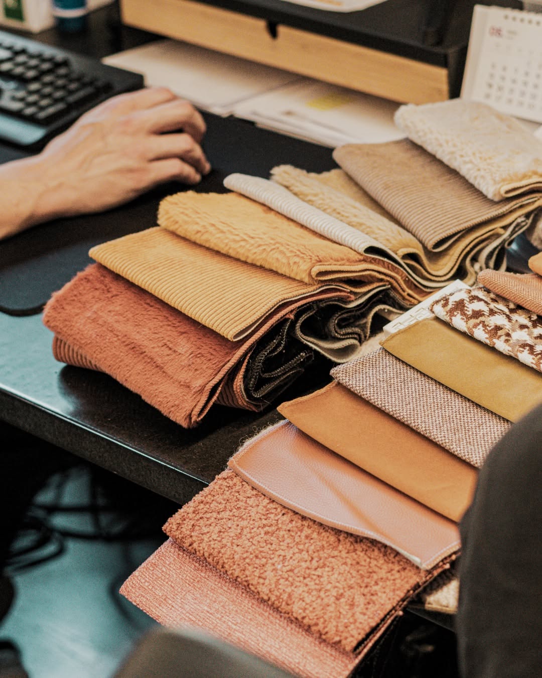 Hands sorting fabric swatches at a desk