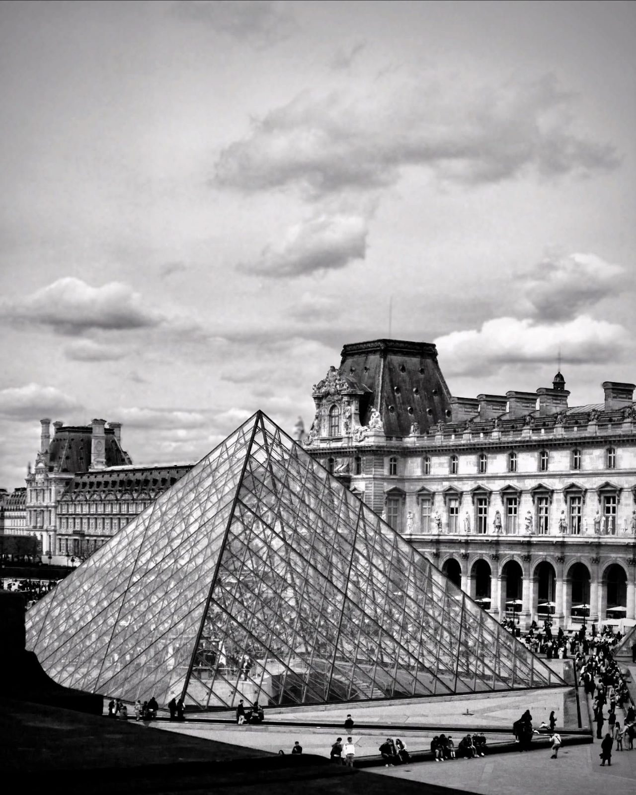 Louvre Pyramid under summer clouds