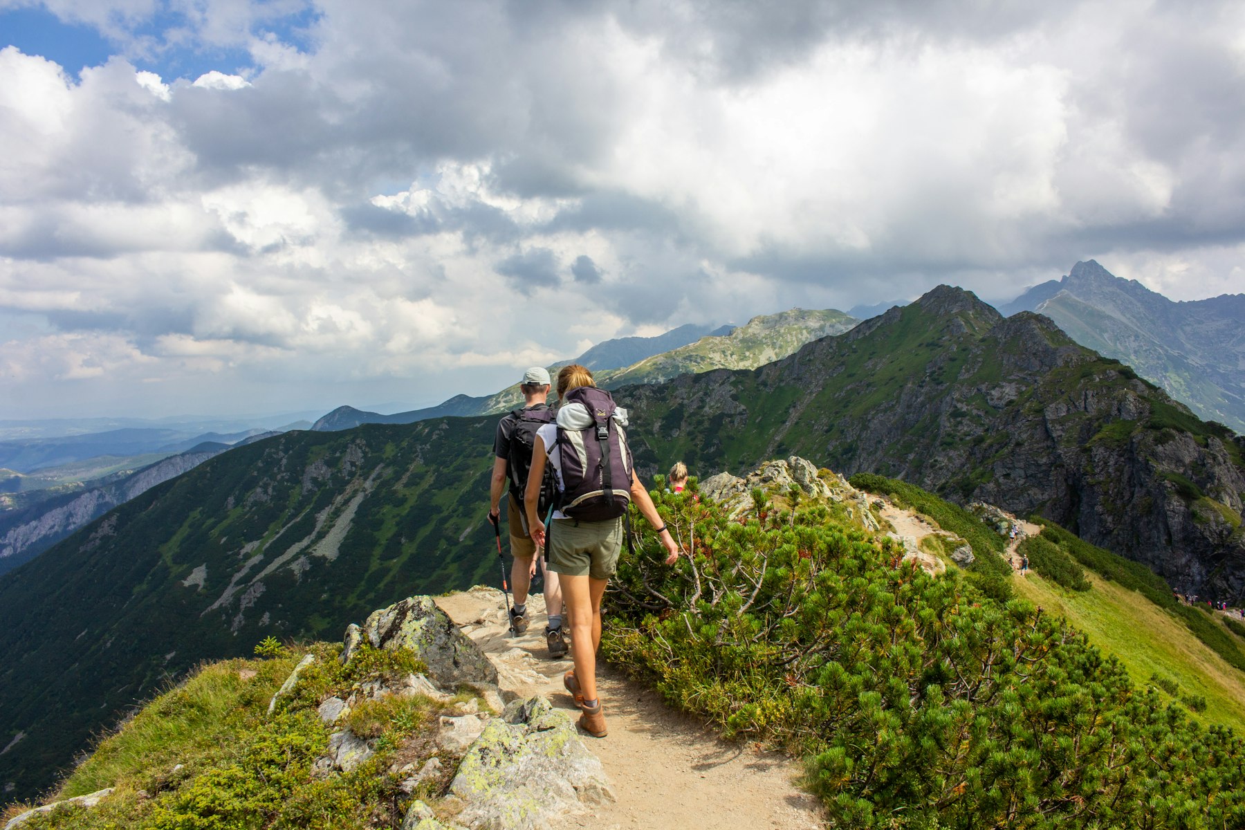Two hikers on a grassy ridge path