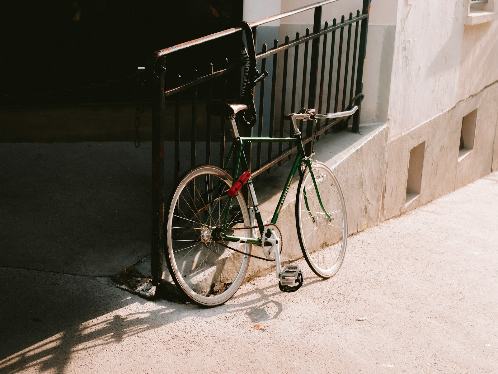 Green steel road bike leaning on black railings in low sun