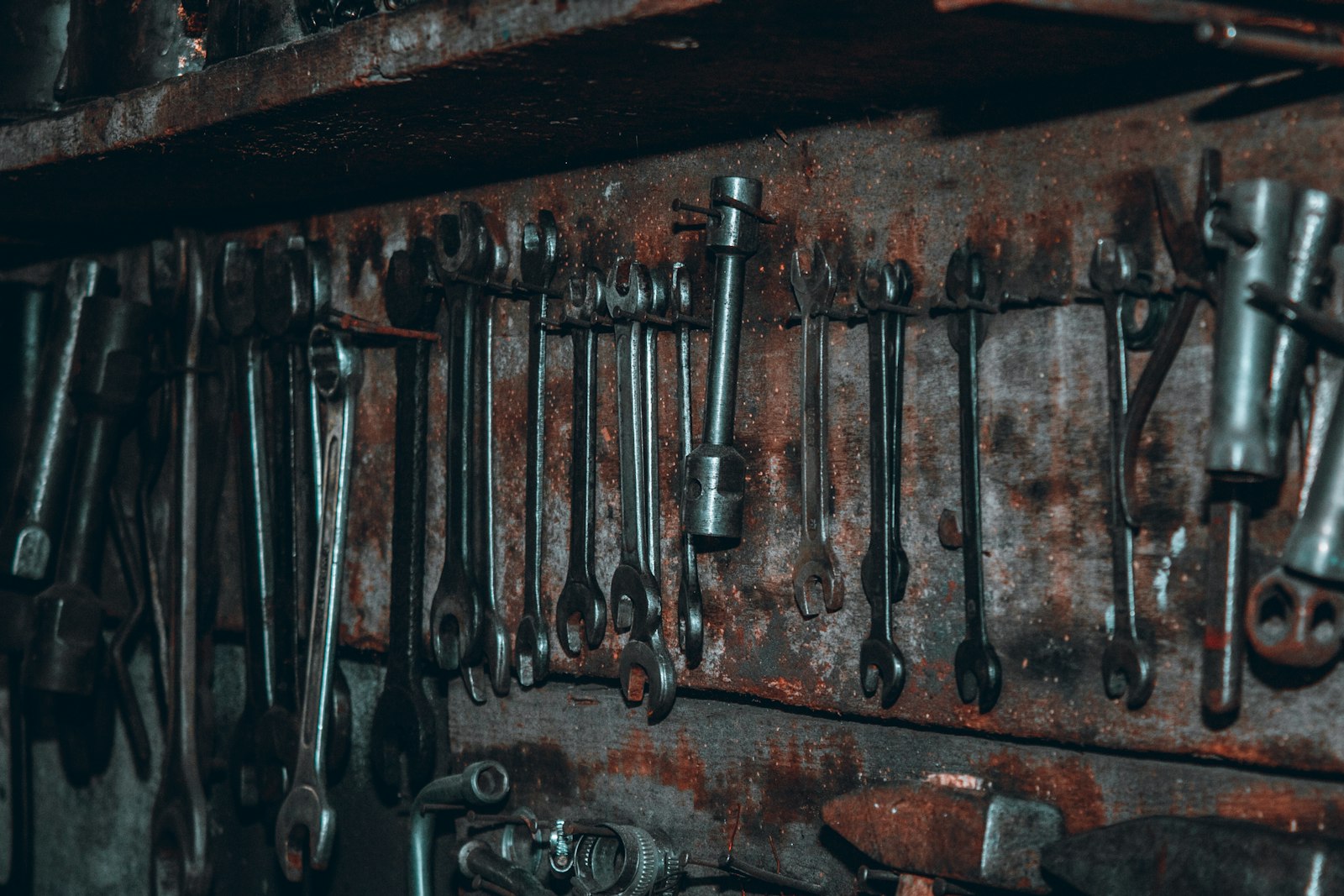 Rows of worn spanners hanging on a rusty steel rack