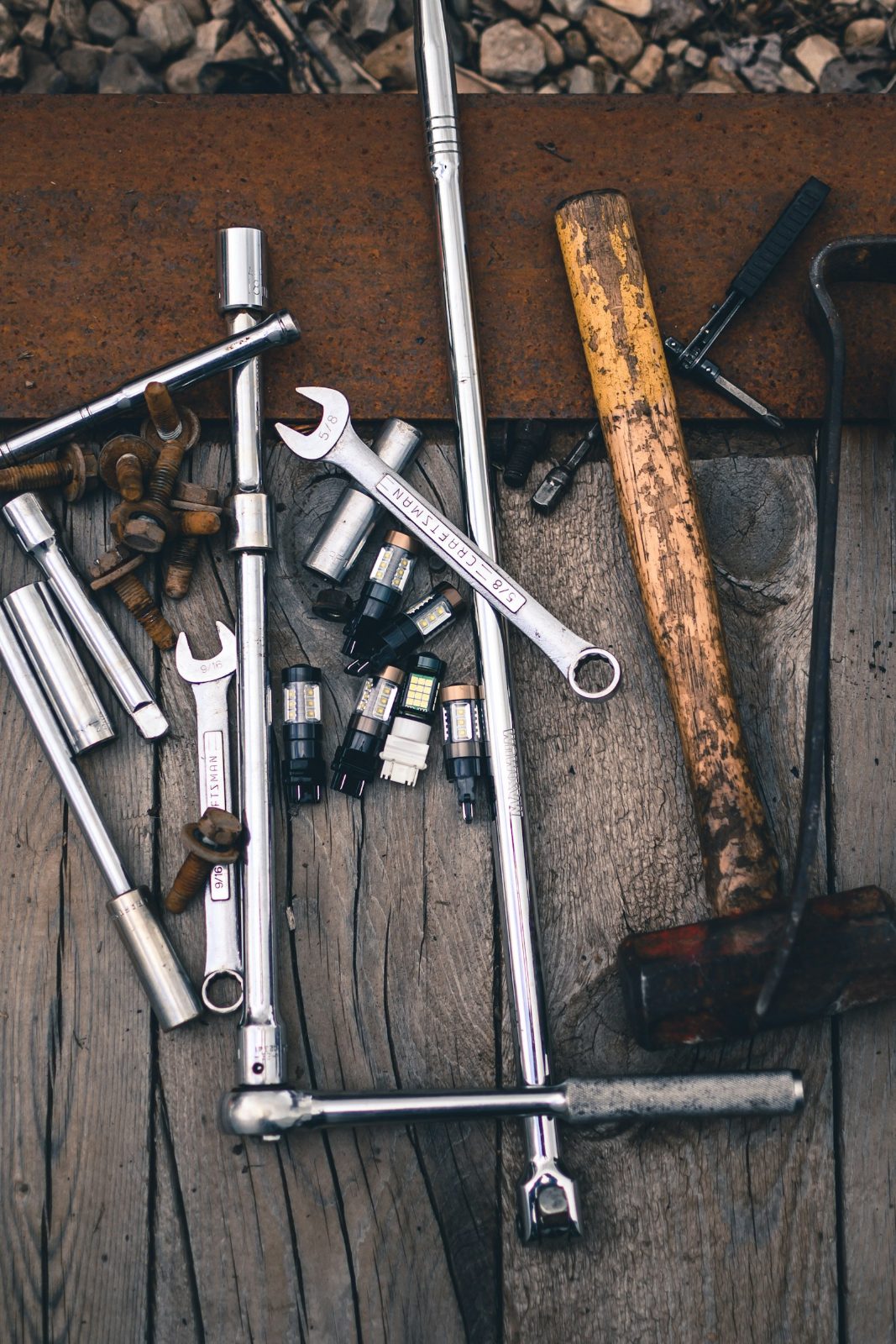 Socket set, spanners and a hammer on a worn wooden bench