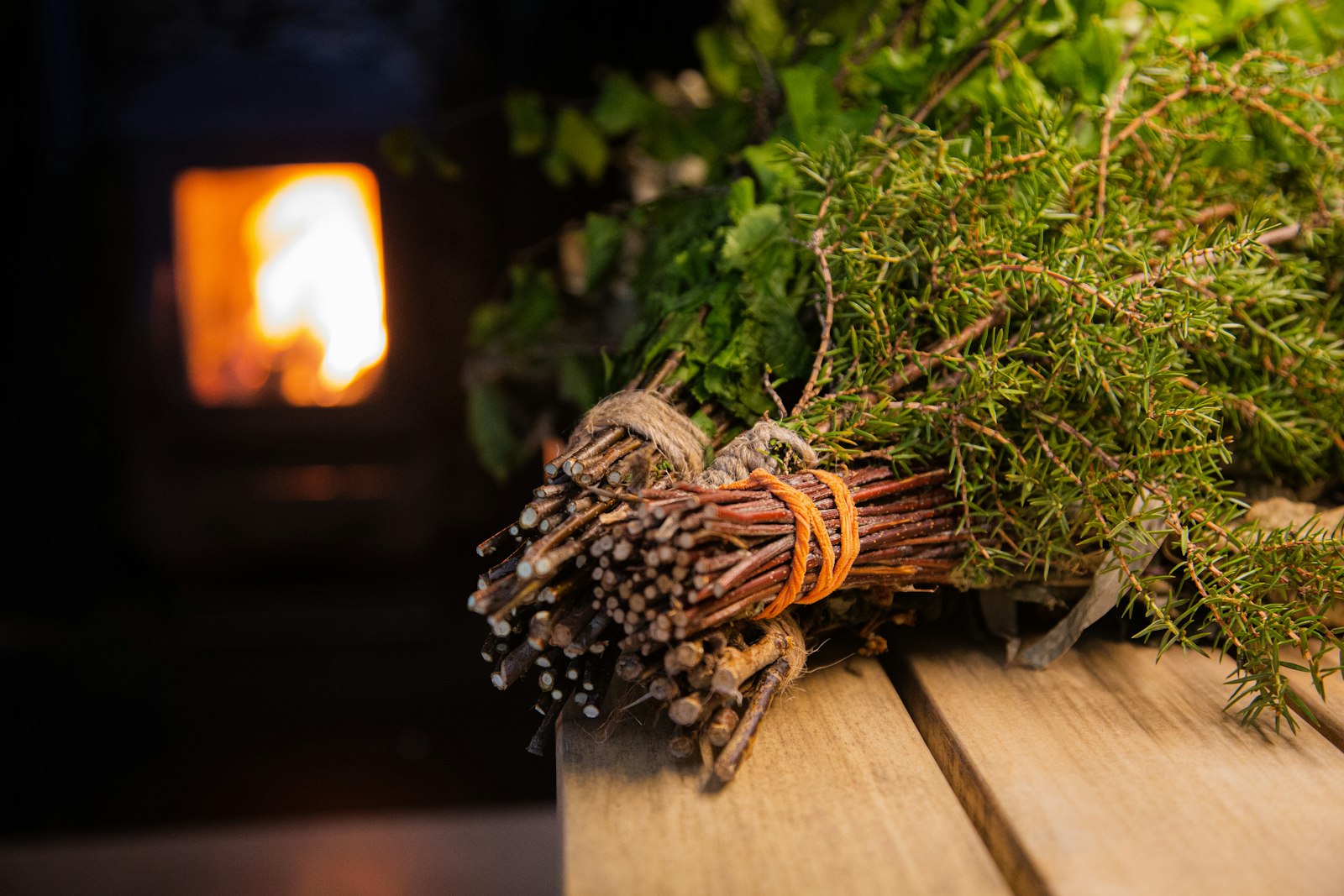 Birch whisk on the bench with the stove fire behind