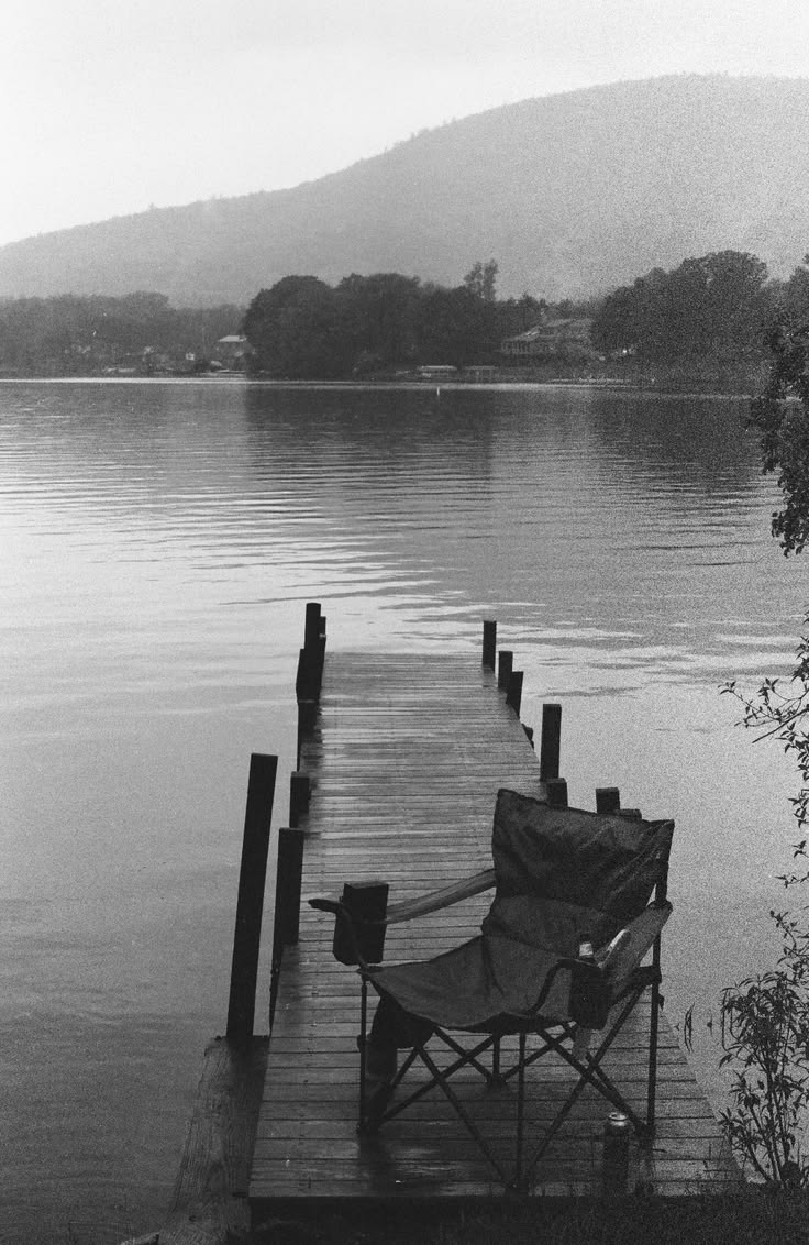Black and white photo of a camping chair on a wet jetty