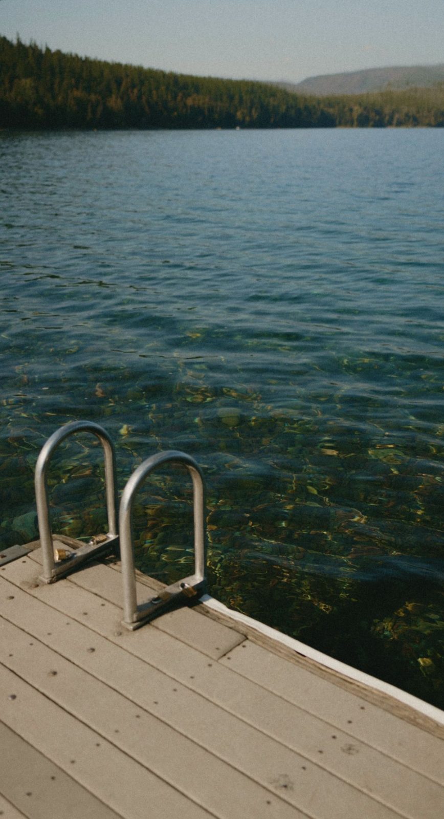Ladder from a pale jetty into clear lake water