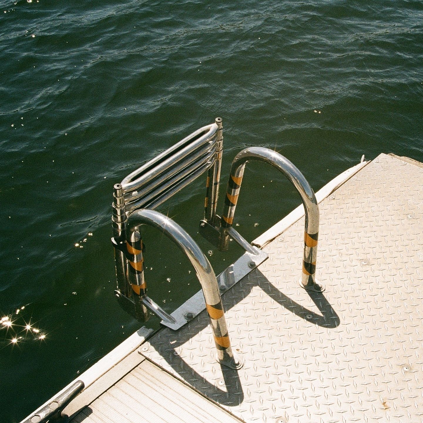Steel ladder from the jetty into dark green lake water