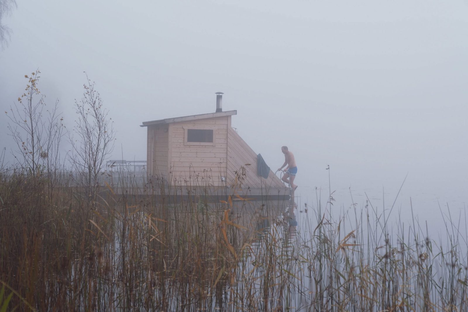 Floating sauna in fog, a swimmer climbing out