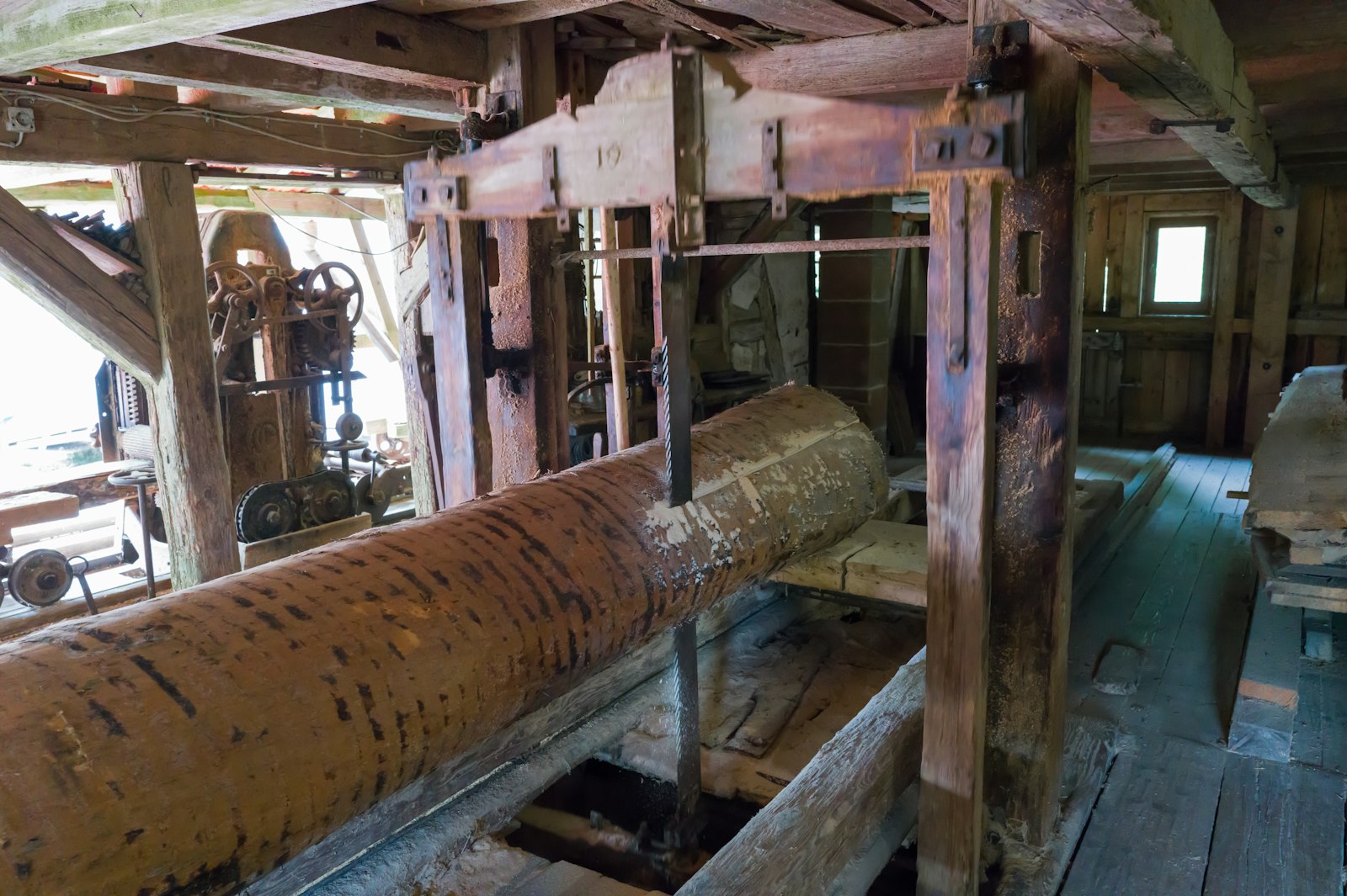 A log on the carriage of an old frame saw inside a timber mill