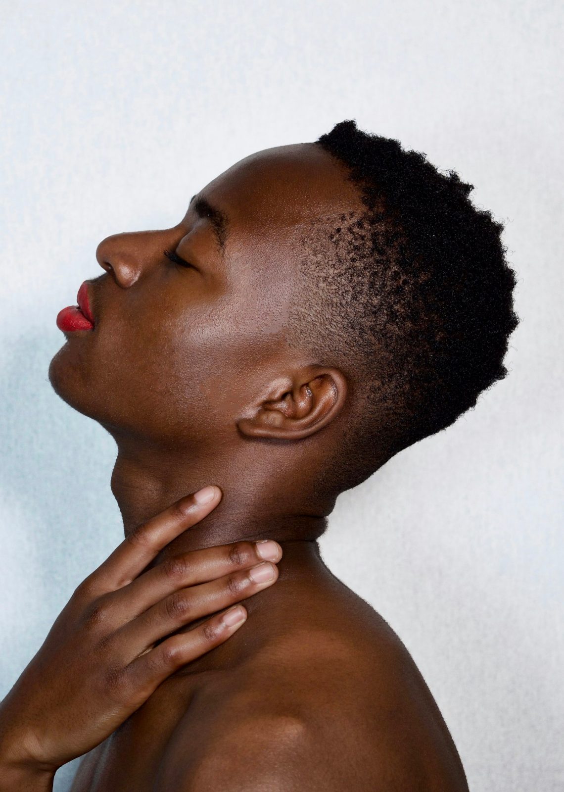 Woman with bare shoulders against a pale wall
