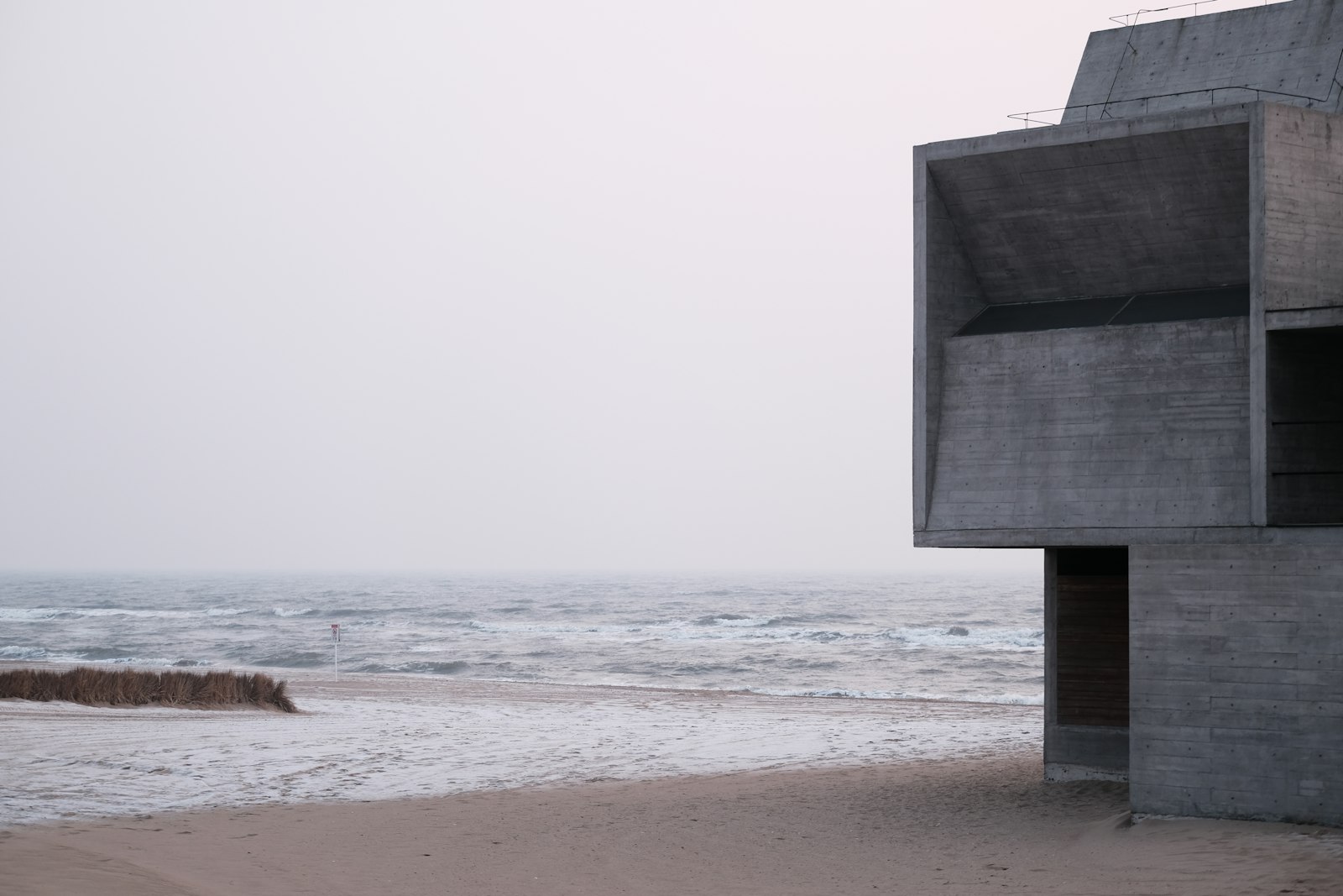 Concrete house on a beach under a pale sky