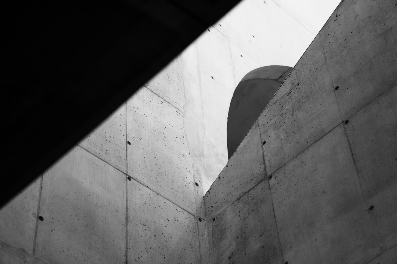 Concrete walls and a curved tower from below
