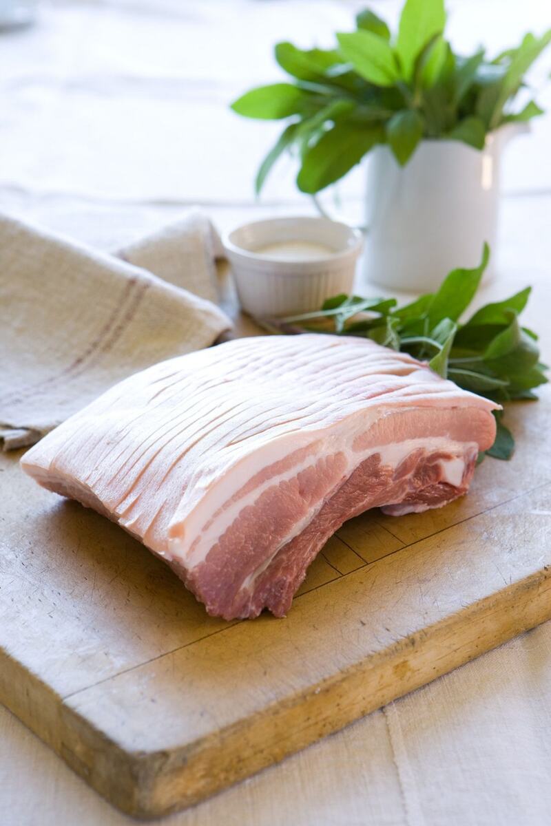 Square of skin-on pork belly on a wooden board