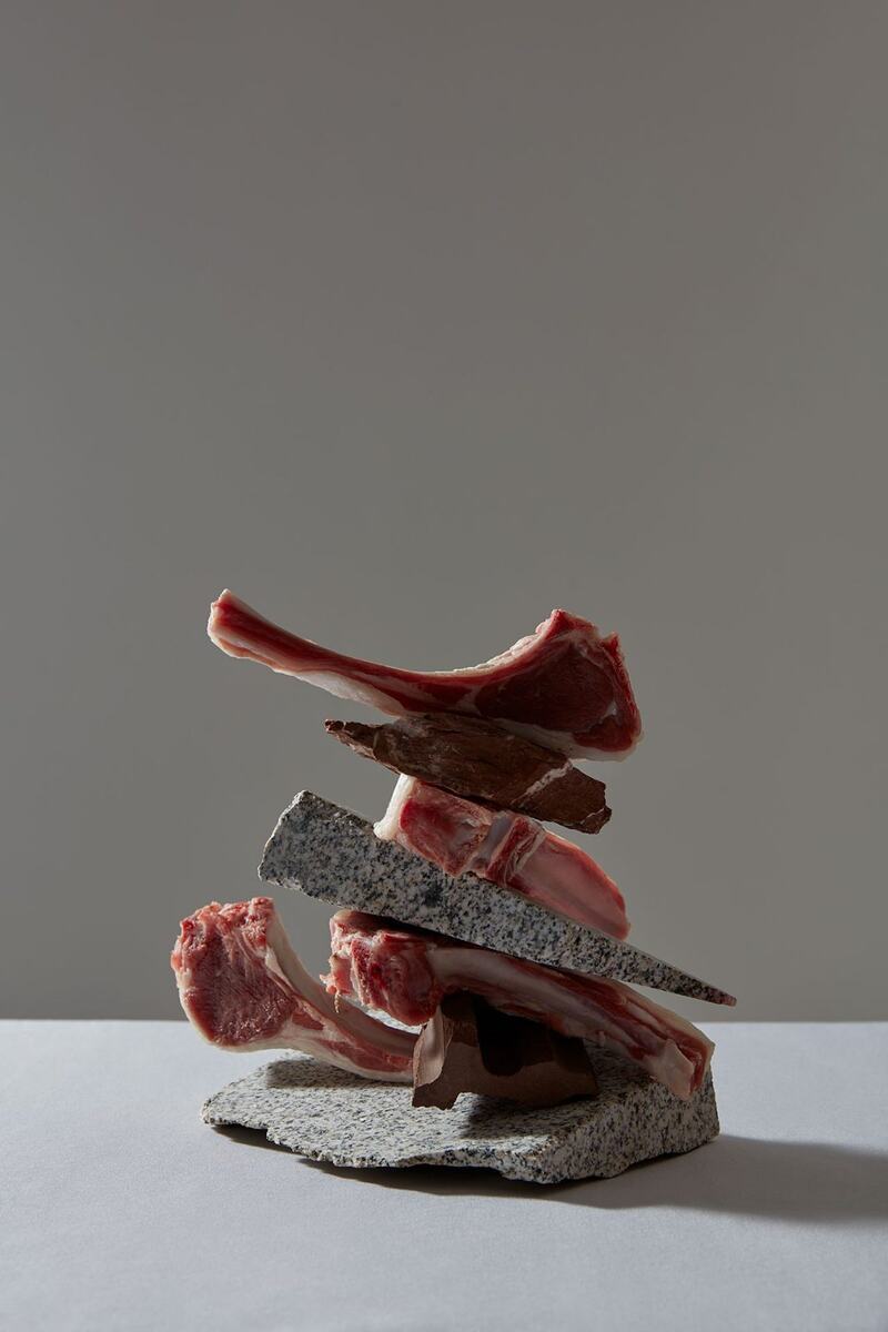 Beef rib bones stacked on stone with a cleaver