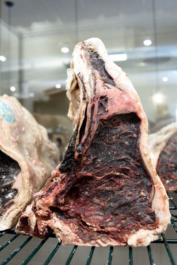 Dry-aged beef on the bone on a rack in an ageing room