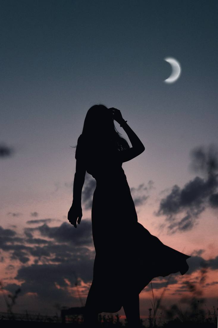 Silhouette of a woman in a long dress at dusk