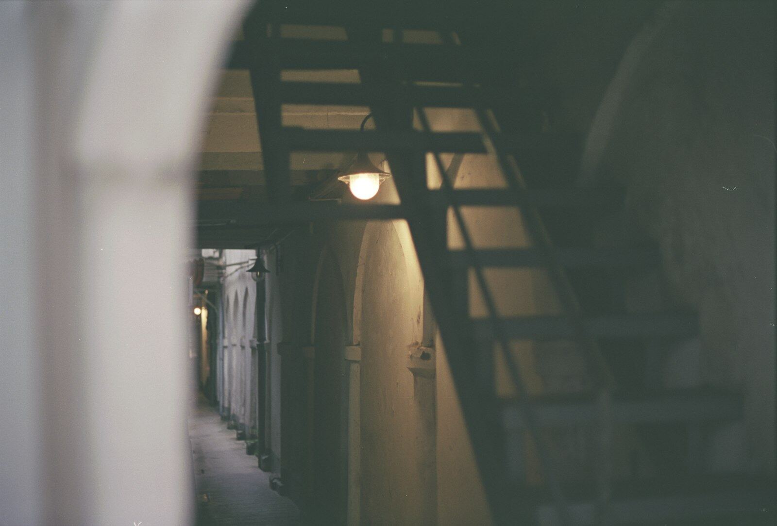 Narrow corridor with a metal stair and a single lamp