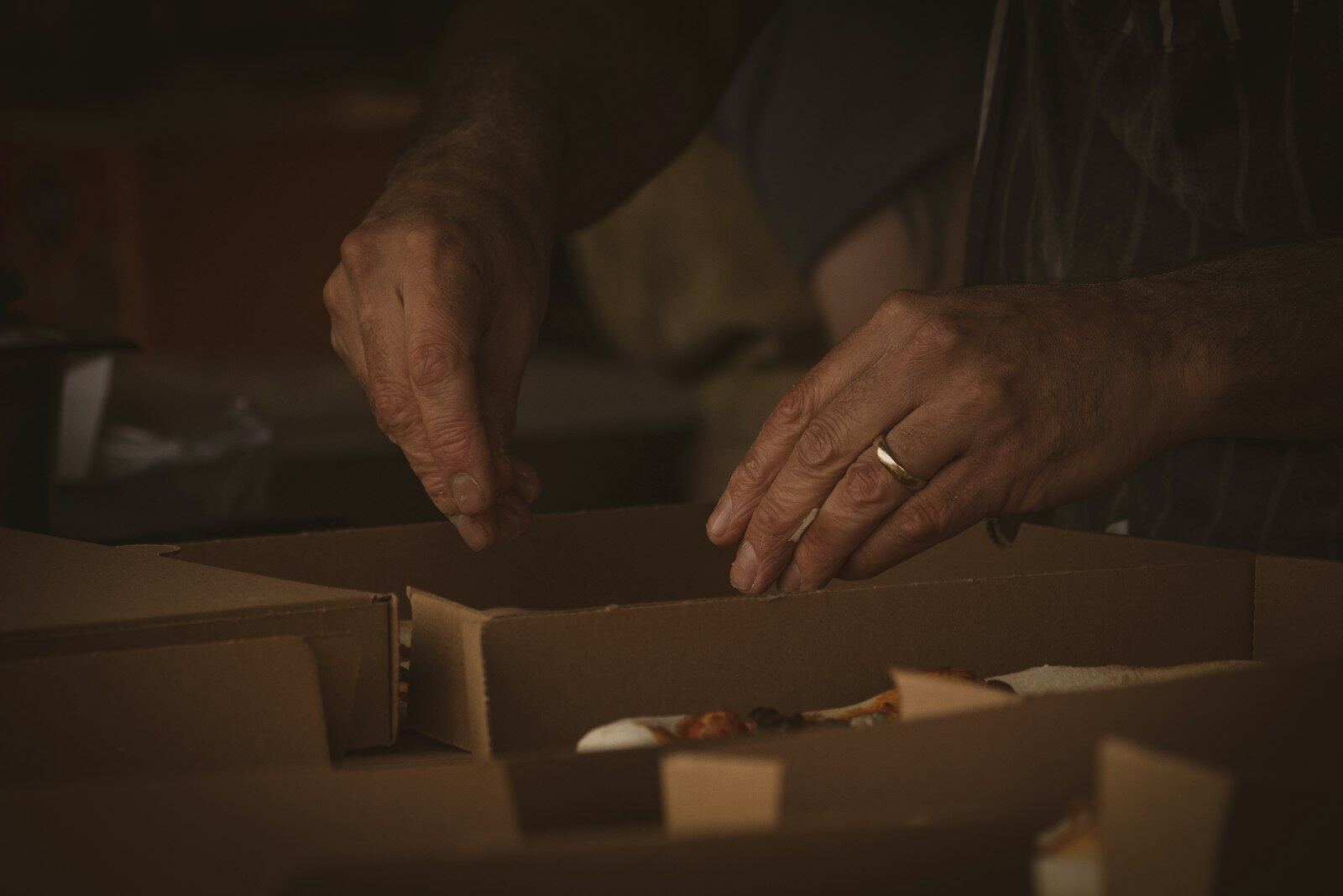 Two hands setting a plate into a cardboard box